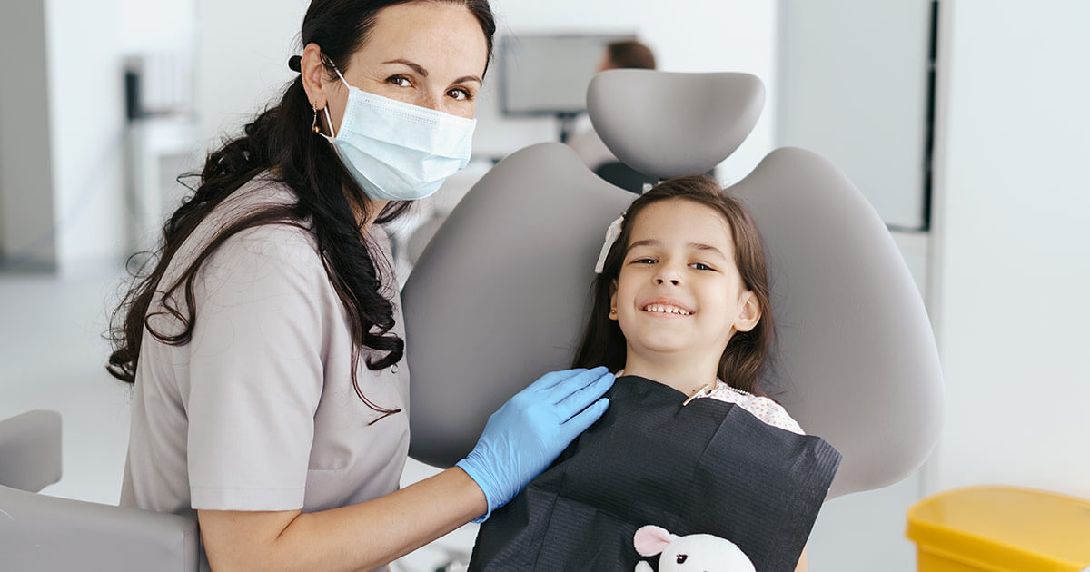 Dentista infantil arreglando diente roto de una niña